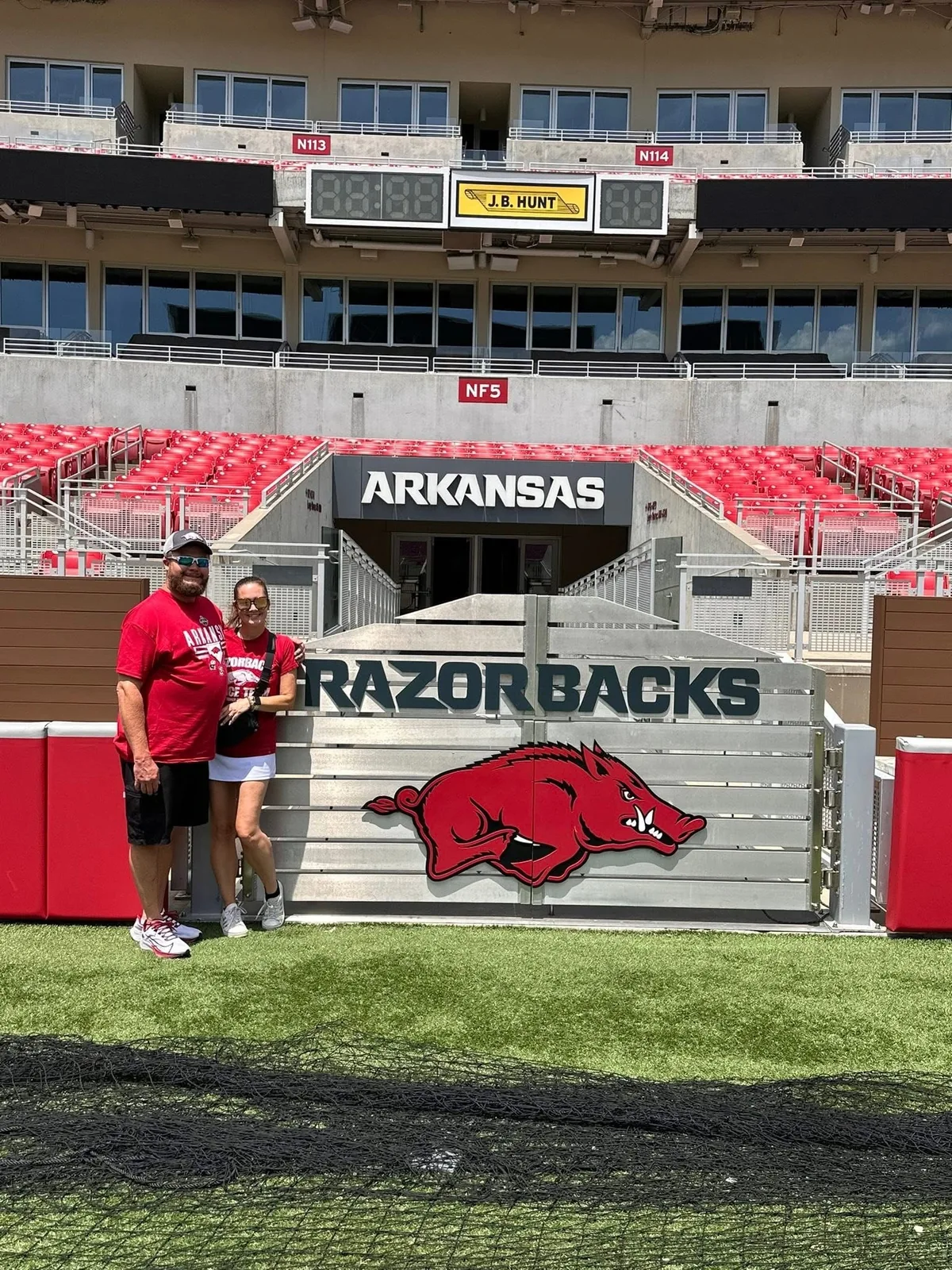 Danny and Diedre beside an Arkansas Razorbacks sign at Donald W. Reynolds Razorback Stadium
