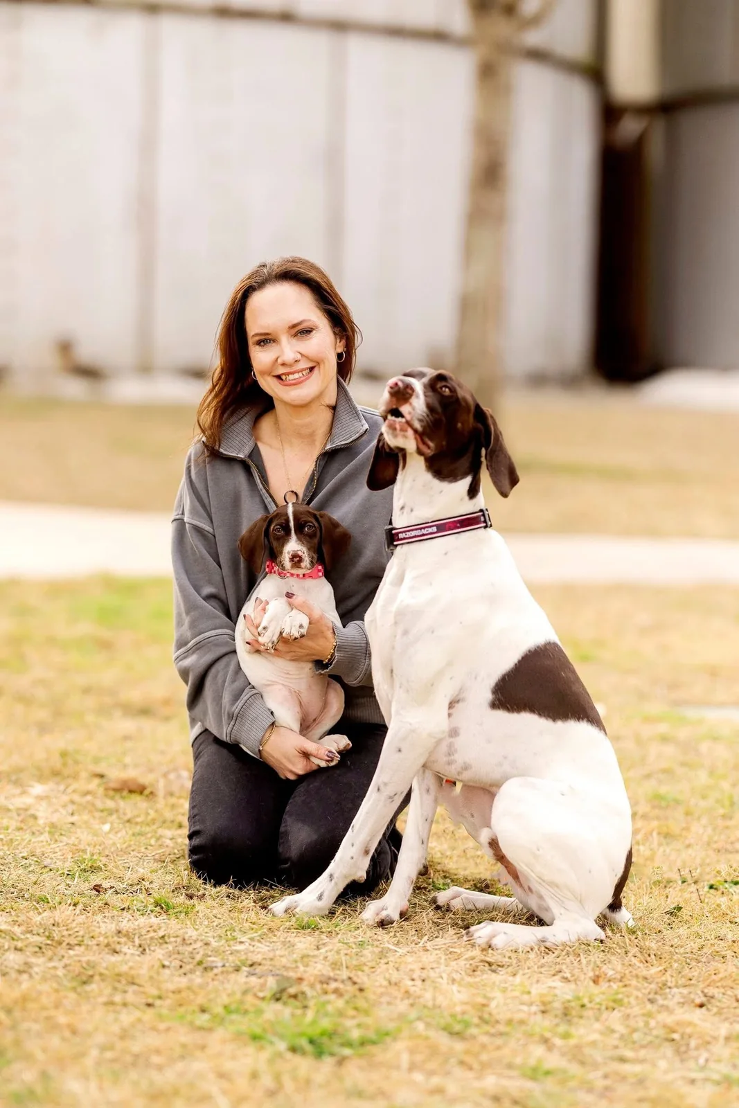 Diedre kneeling on the grass with Lovie Rae in her arms and Rowdy Ray by her side