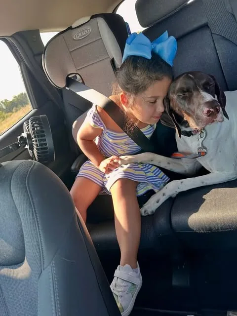Claire cuddling close to Rowdy while they sit together in a car