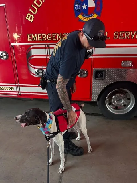 A Buda firefighter pets Rowdy beside a red fire truck